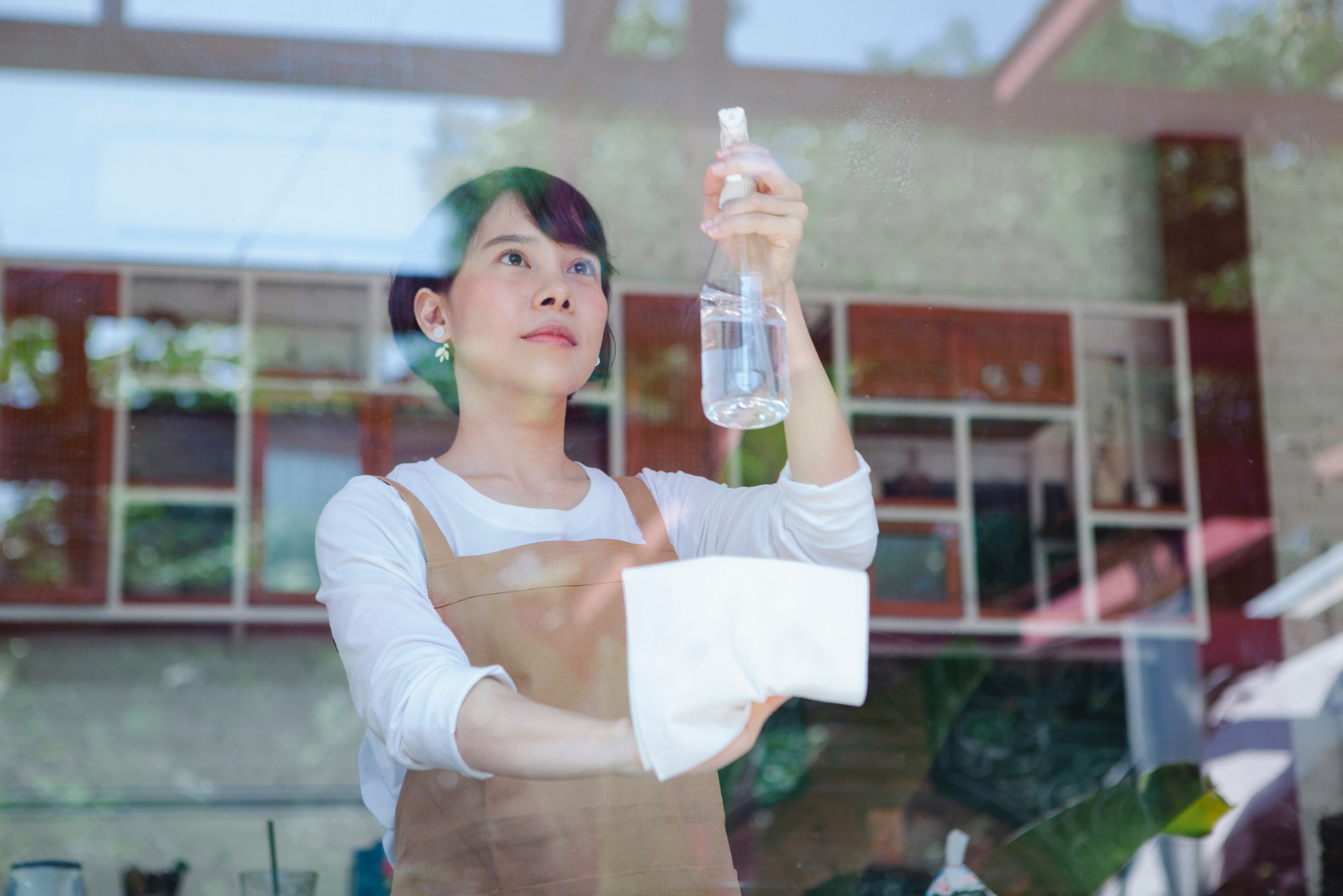 Woman Wearing Brown Apron Cleaning Window Glass